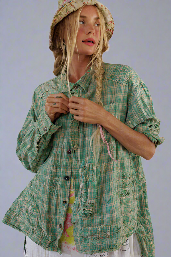 Woman wearing a green plaid shirt and a patterned hat on a white background