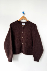 Brown cardigan on a hanger against a white background
