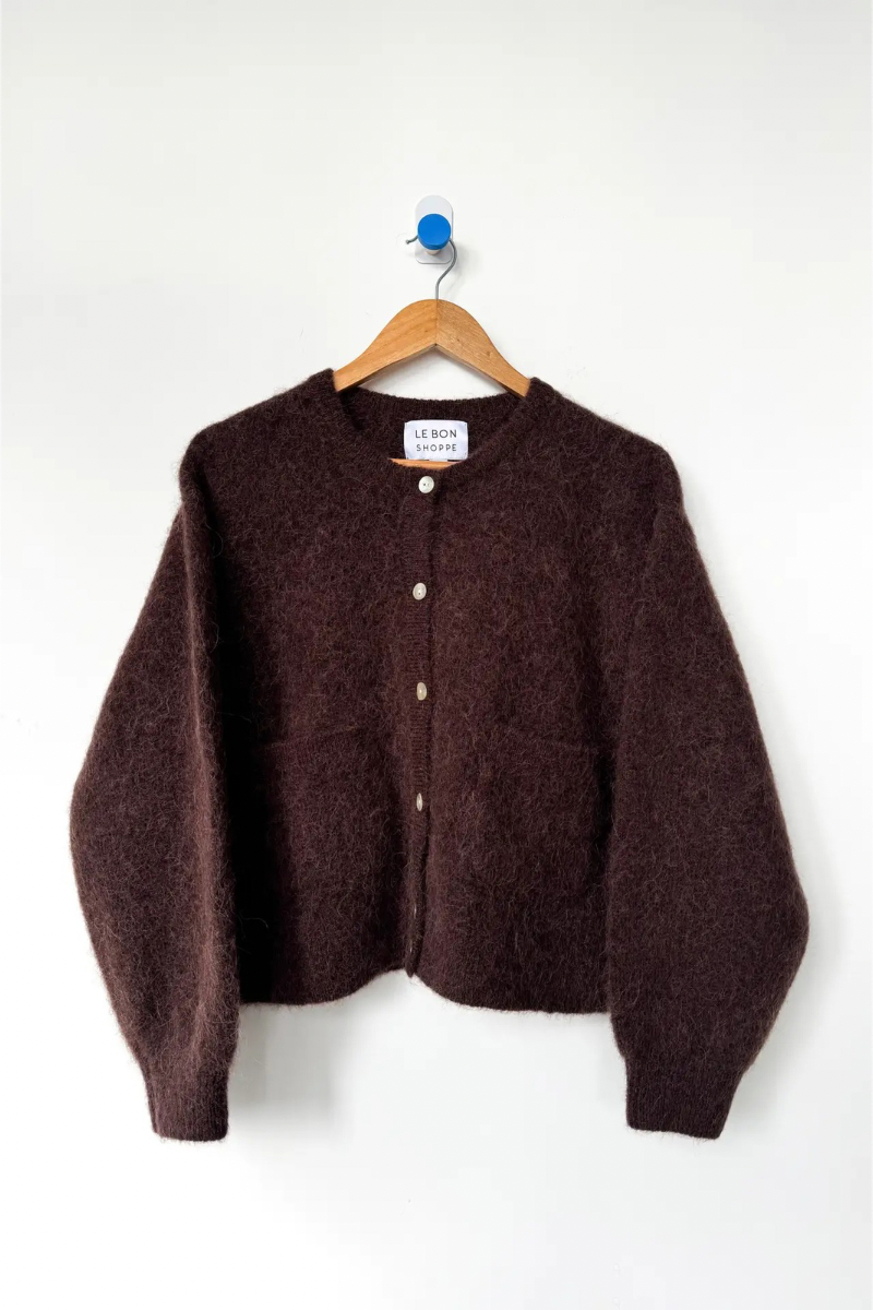 Brown cardigan on a hanger against a white background