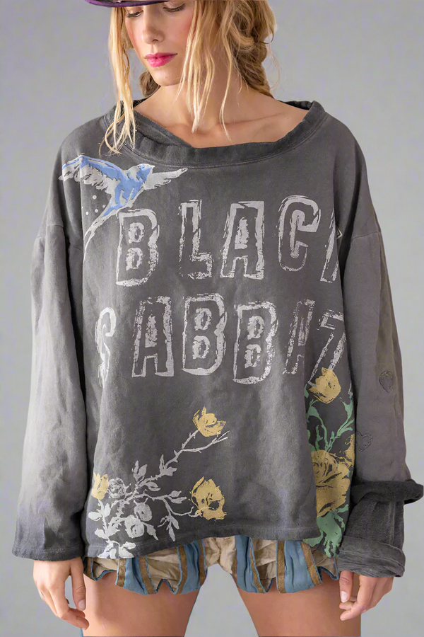 Person wearing a dark gray 'Black Sabbath' oversized shirt with floral designs on a plain background