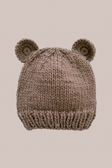 Knitted baby hat with bear ears on a beige background