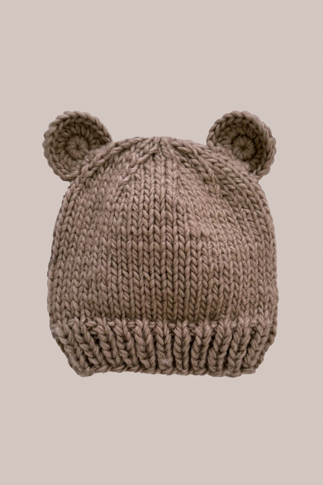 Knitted baby hat with bear ears on a beige background