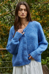 Woman wearing a blue knitted cardigan in a natural setting