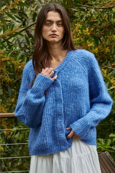 Woman wearing a blue knitted cardigan in a natural setting