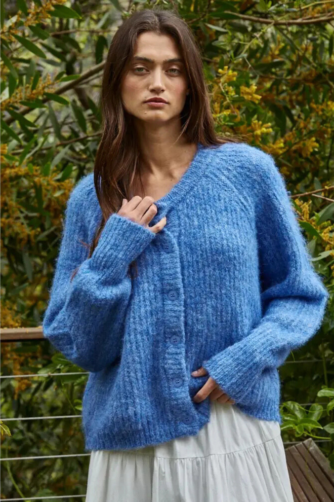 Woman wearing a blue knitted cardigan in a natural setting