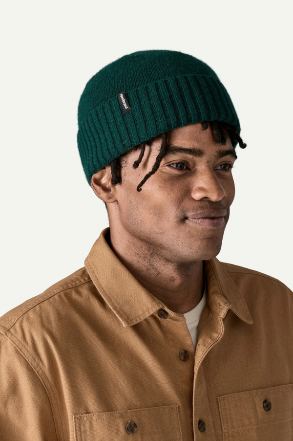 Man wearing a green beanie and brown jacket on a white background