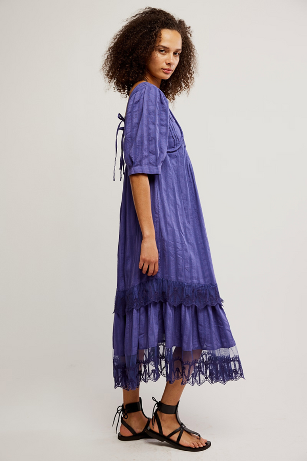 Woman wearing a purple dress with lace details on a white background