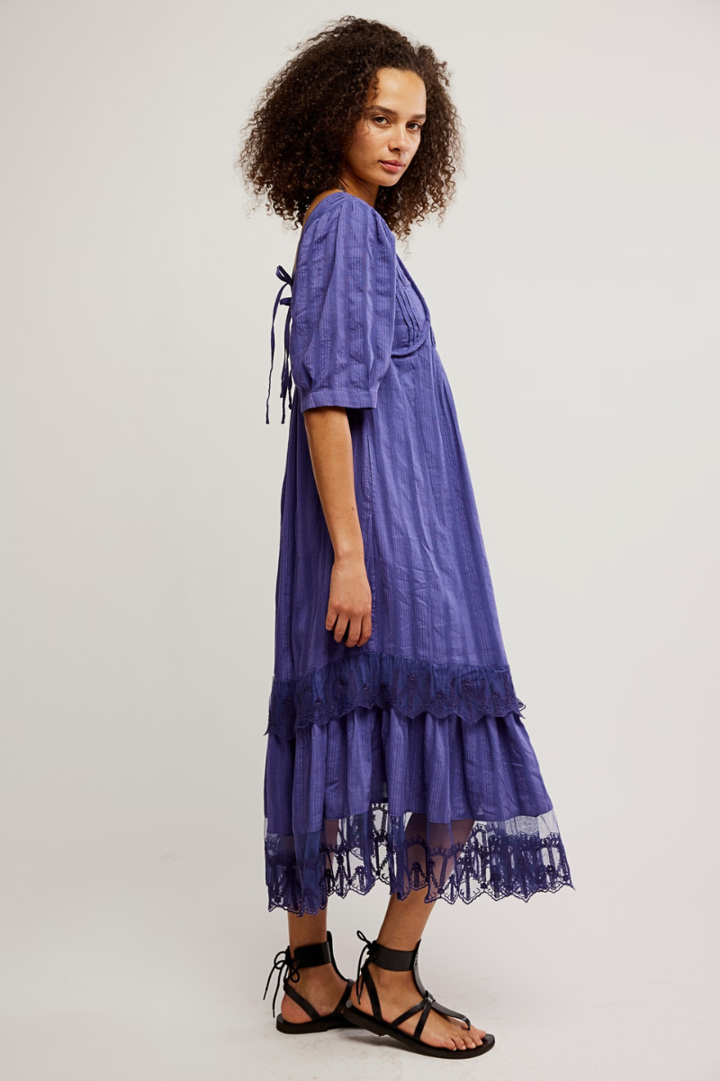Woman wearing a purple dress with lace details on a white background