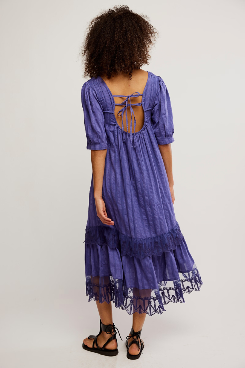 Woman wearing a purple dress with a lace hem on a white background