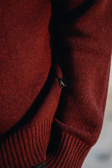 Close-up of a red sweater with a brand logo on a blurred background
