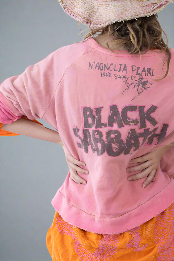 Person wearing a pink oversized shirt with 'Black Sabbath' text and 'Magnolia Pearl' branding.