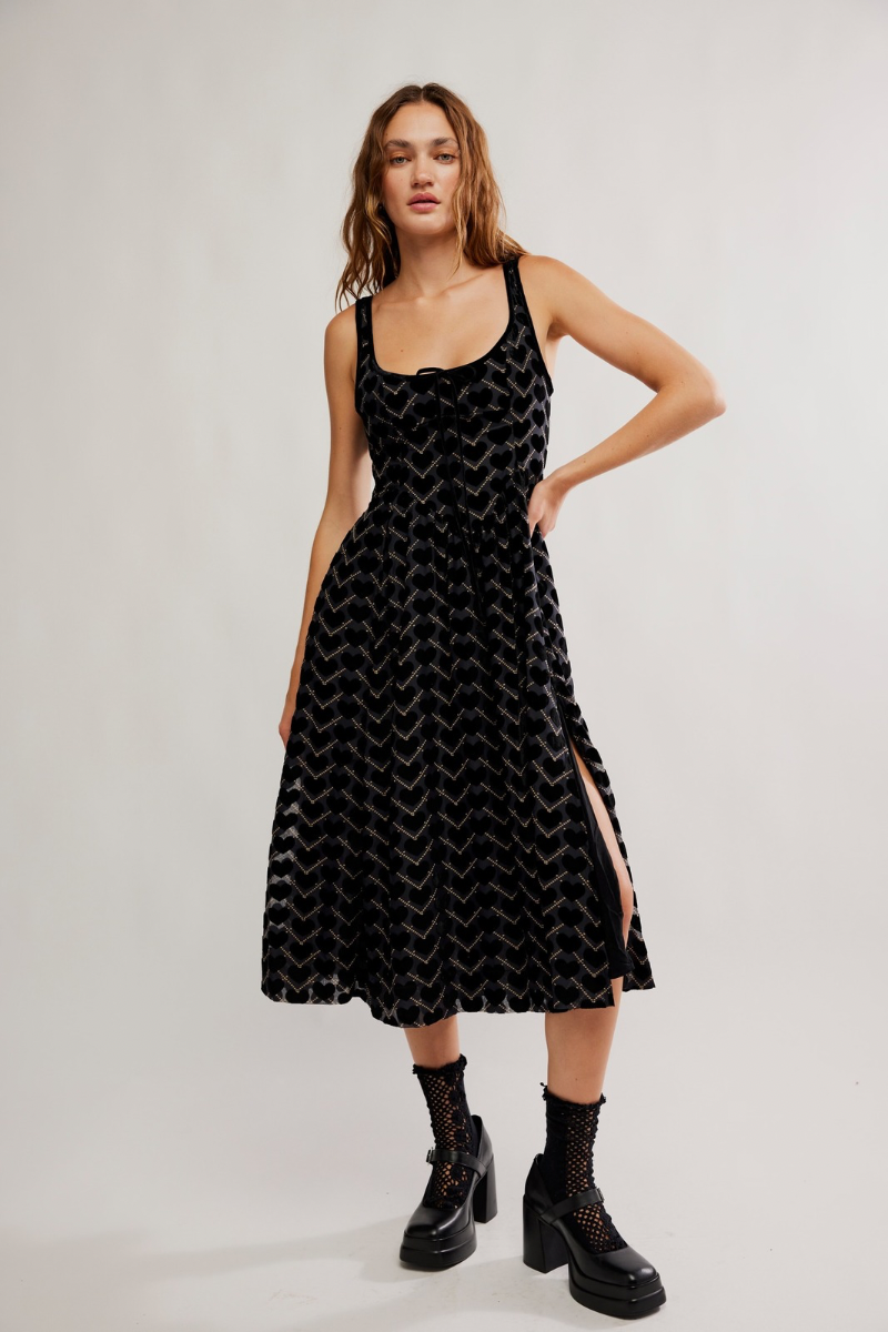 Woman wearing a black patterned dress with cut-out sides on a white background