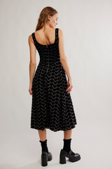Woman wearing a black patterned dress on a plain background