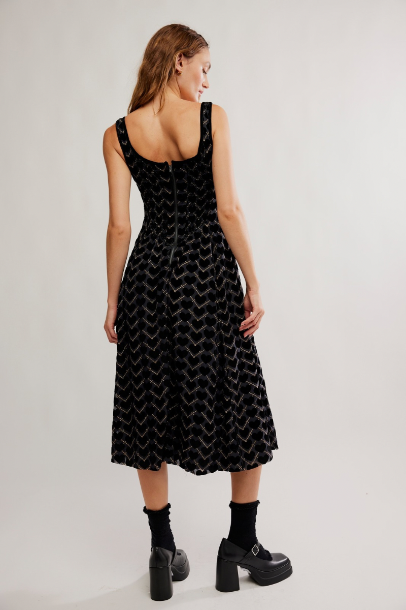 Woman wearing a black patterned dress on a plain background