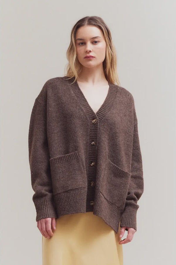Woman wearing a brown cardigan against a plain background