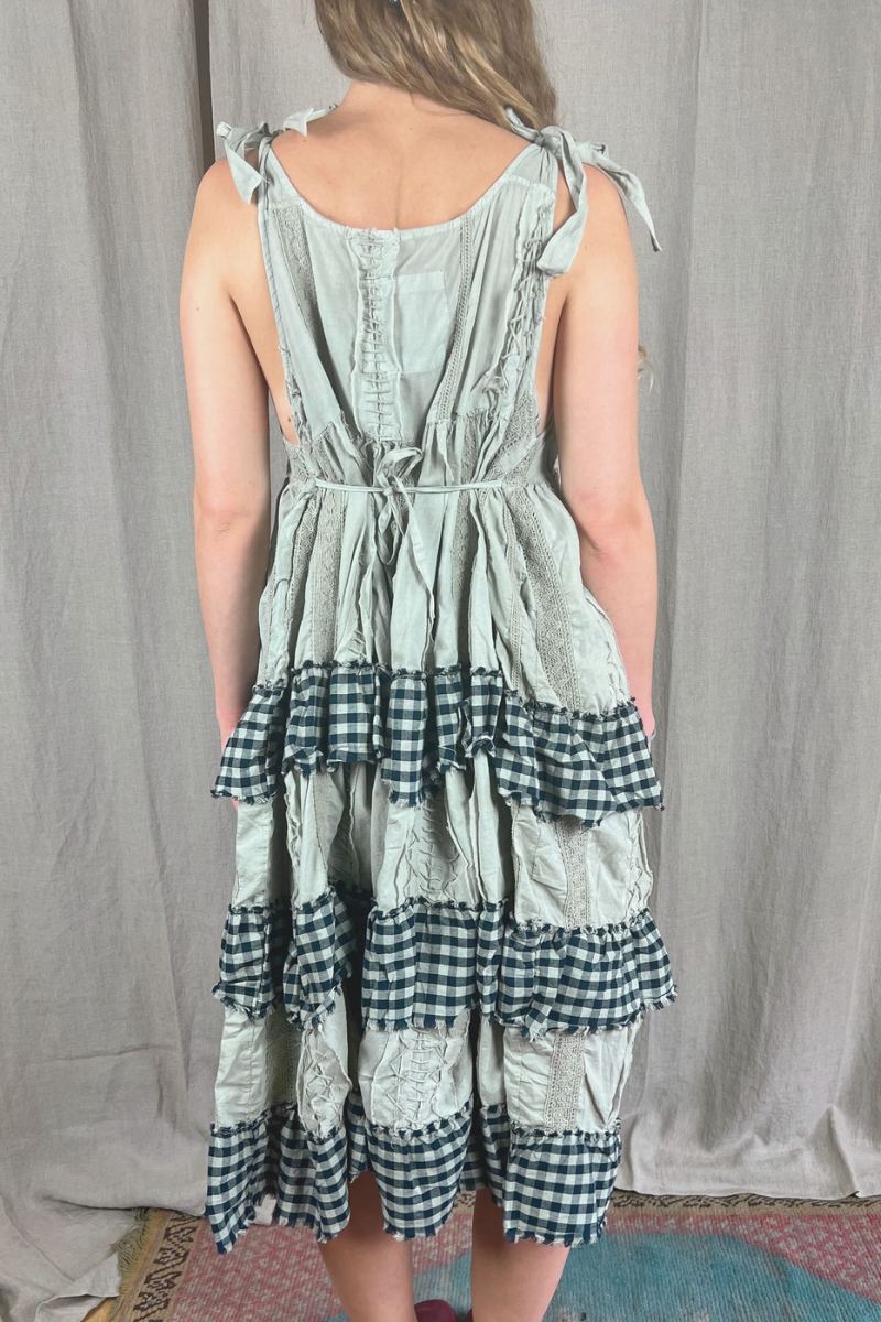 Person wearing a green and black checkered dress against a plain background