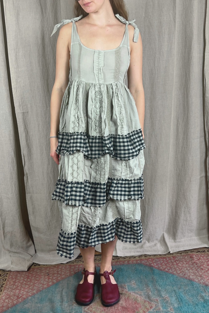 Woman wearing a layered dress with a checkered pattern against a plain background