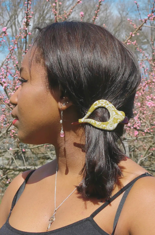 Woman with a decorative hair clip outdoors with cherry blossoms in the background