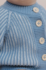 Close-up of a blue knitted sweater with buttons on a neutral background