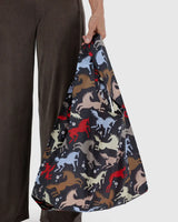 Person holding a bag with horse pattern against a plain background