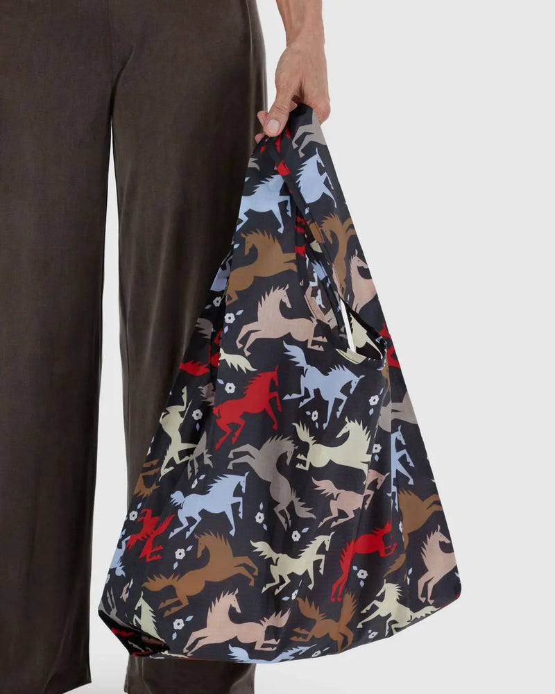 Person holding a bag with horse pattern against a plain background