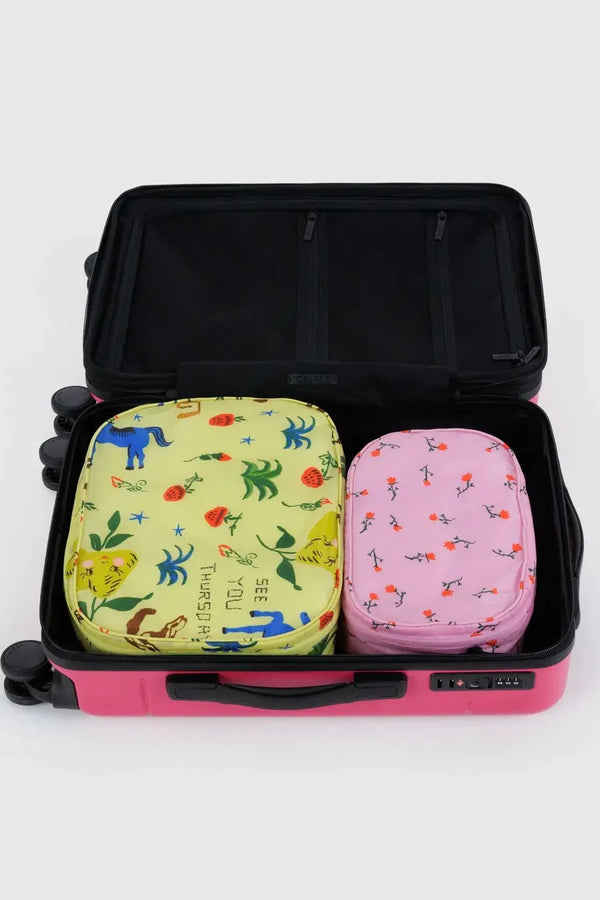 Two patterned travel bags inside an open suitcase on a white background