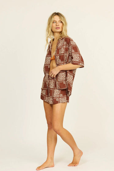 Woman wearing a brown and white patterned matching set, on a beige background