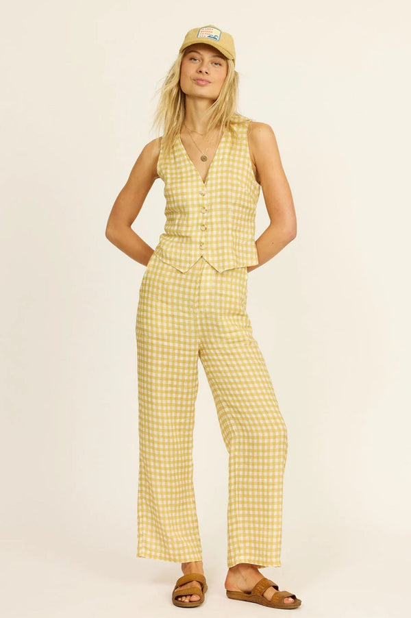 Woman wearing a yellow checkered two piece set and cap on a beige background