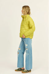 Person wearing a bright yellow puffer jacket and blue jeans on a white background