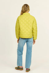 Person wearing a yellow quilted jacket and blue jeans on a white background