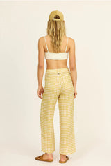 Woman wearing a yellow checkered outfit with a beige background