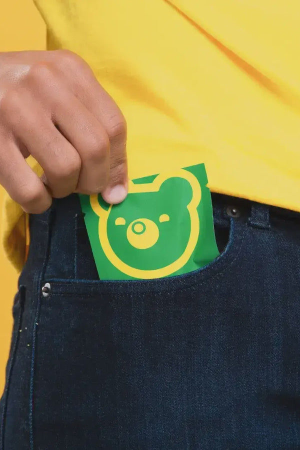 Person wearing a yellow shirt with a green and yellow bear package of gummies in their pocket.