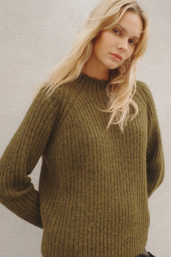Woman wearing a green sweater against a plain background