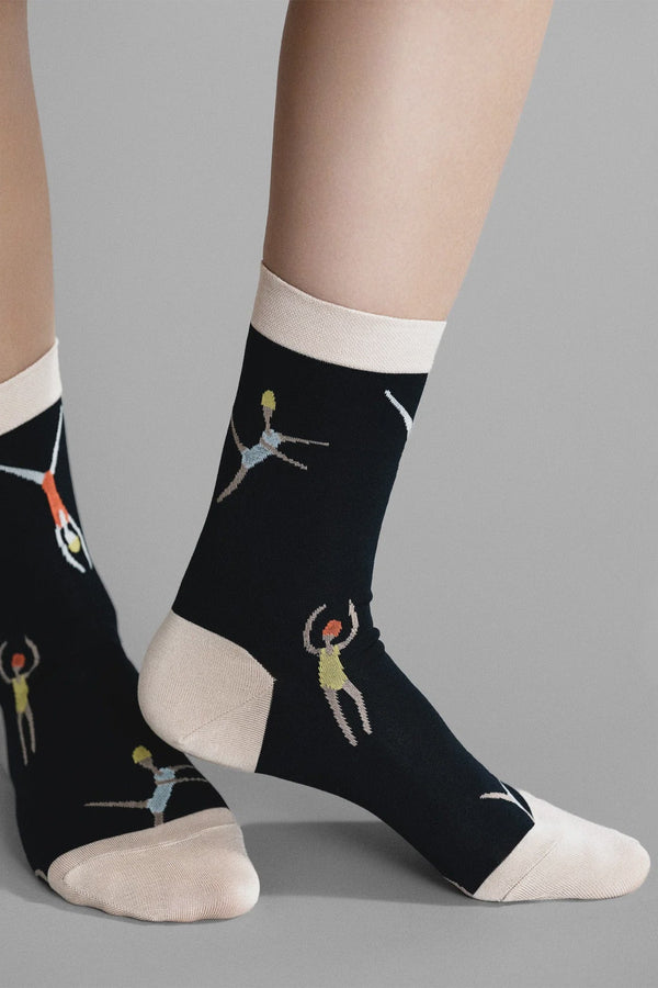 Black socks with white tops and feet featuring artistic illustrations of people swimming on a gray background.