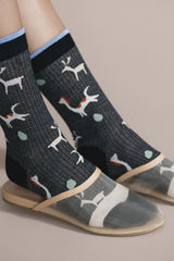 Person wearing black socks with white dog pattern on a beige background