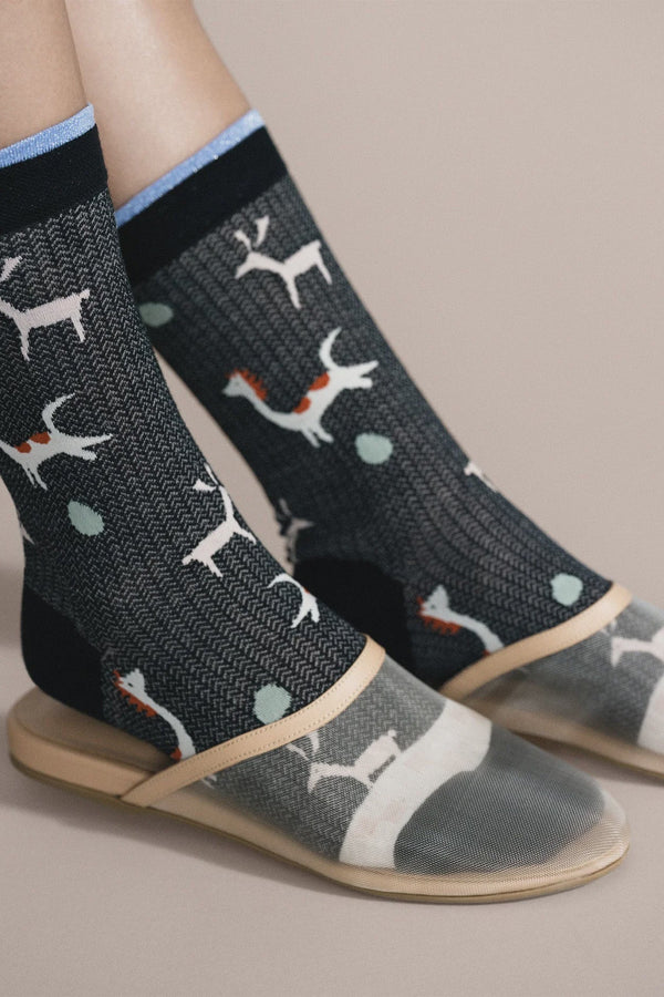 Person wearing black socks with white dog pattern on a beige background