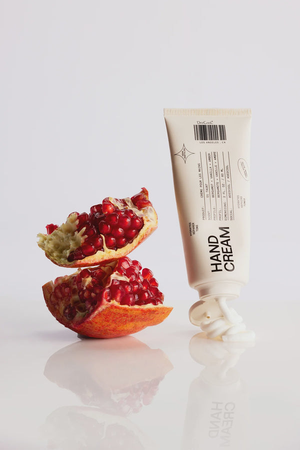 Hand cream tube next to a pomegranate on a white background