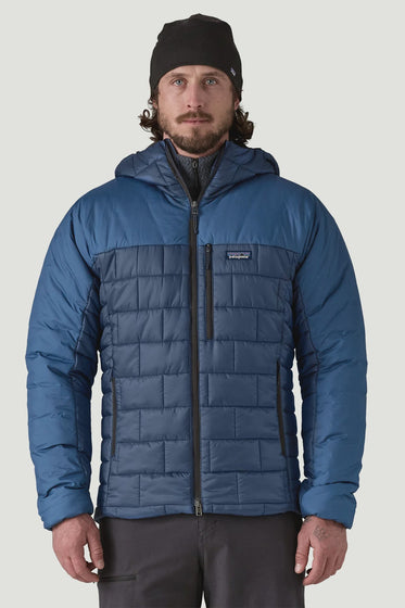 Man wearing a blue quilted jacket and black beanie on a light gray background