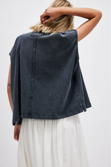 Person wearing a dark denim shirt over a white dress on a plain background