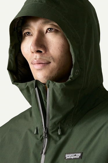 Person wearing a green hooded jacket with Patagonia logo on a white background