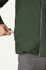 Person wearing a green jacket with a close-up of the zipper area on a white background