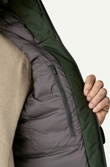 Close-up of a person wearing a green jacket with a beige sweater underneath on a white background