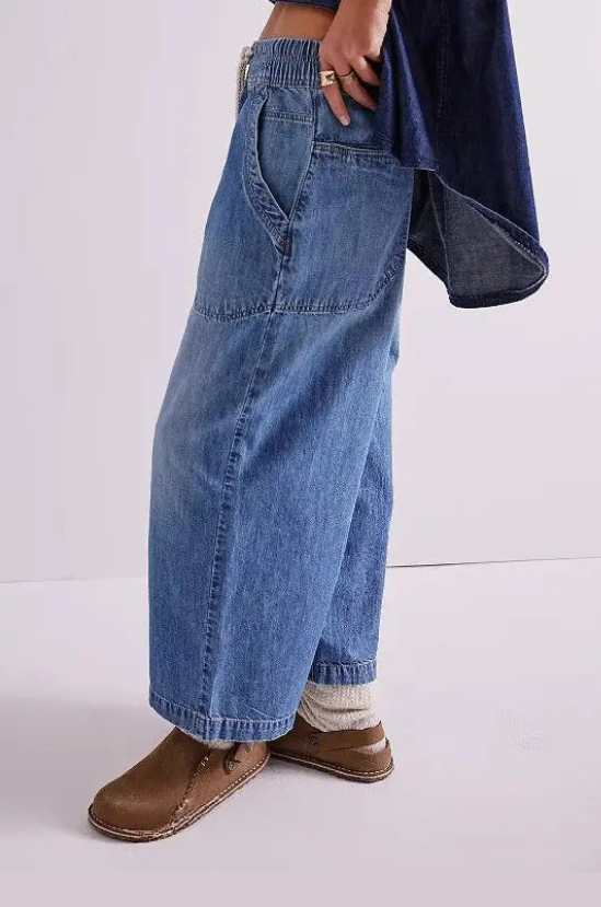 Person wearing blue jeans and brown shoes on a white background