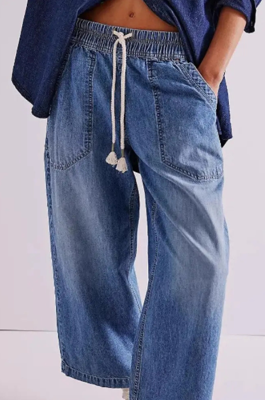 Blue denim pants with a drawstring waist on a white background