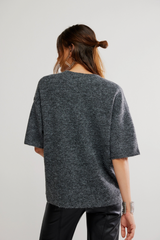 Person wearing a gray oversized sweater on a plain background