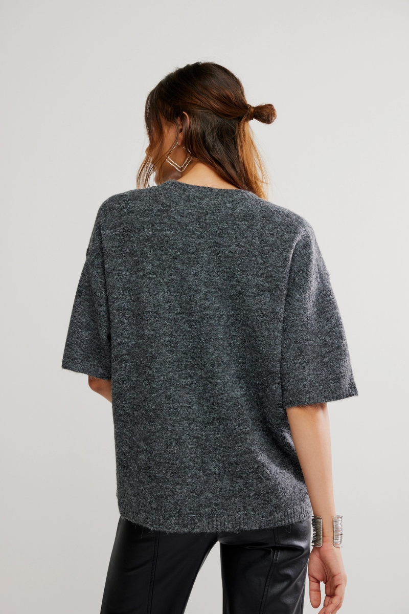 Person wearing a gray oversized sweater on a plain background