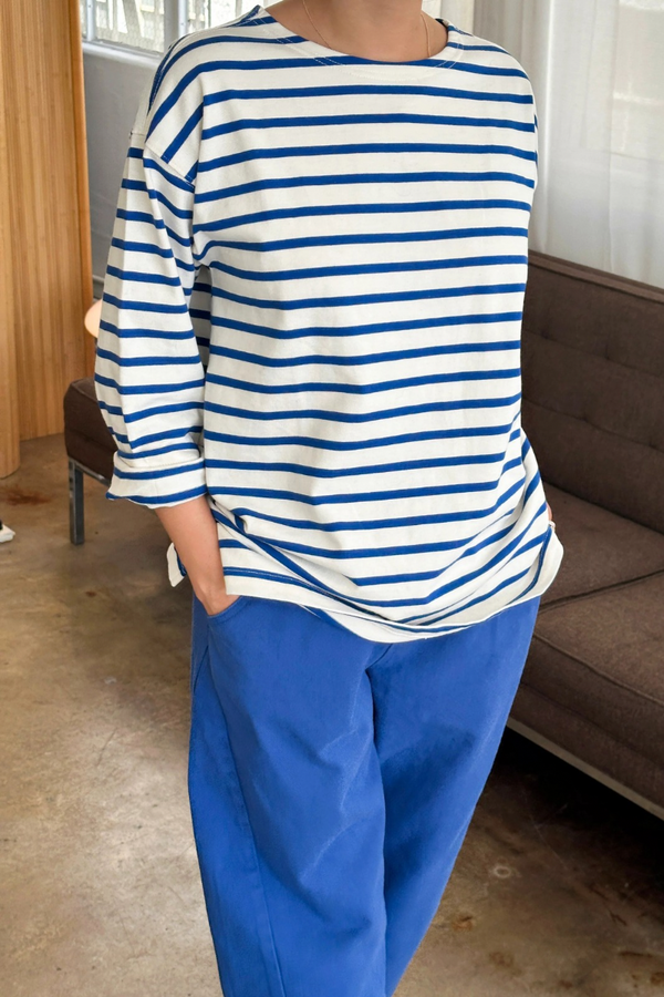 Person wearing a blue and white striped shirt and blue pants in a room with a couch.