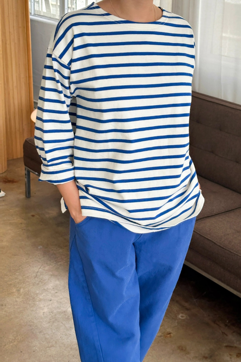 Person wearing a blue and white striped shirt and blue pants in a room with a couch.