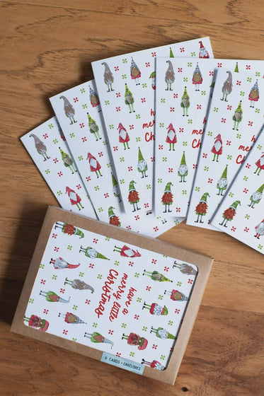 Set of Christmas-themed greeting cards with gnomes on a wooden surface