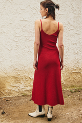 Woman wearing a red dress standing against a textured wall.